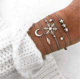 Silver bracelet stack with star and starburst charms worn on a wrist