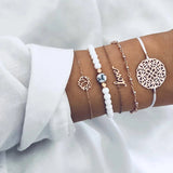 Silver bracelet stack with openwork round charm and fine chains on a wrist
