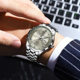 Silver watch with grey dial worn on a wrist with a pinstripe suit