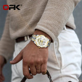 Gold OPK skeleton watch worn on a wrist with a cream knitted sleeve