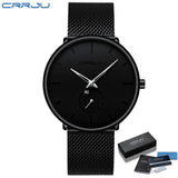 Black mesh band watch with black dial shown front facing on wood surface