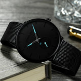 Black mesh band watch with black dial and teal accented hands