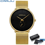 Gold mesh band watch with black dial resting on a wooden table