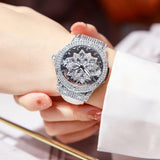 Hand holding silver crystal watch with rotating snowflake dial and white strap