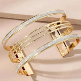 Set of thin gold bangles stacked together on a pale pink background