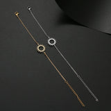 Gold sunburst charm bracelet laid out full length showing clasp and extender chain