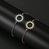 Gold and silver sunburst charm bracelets shown side by side on a dark surface