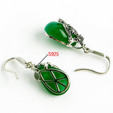 Silver drop earrings with green stones shown to display the ear hook fittings