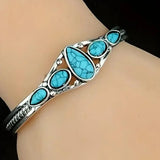 Ornate silver bracelet with turquoise stones worn on a wrist