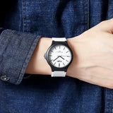 Black case white dial sports watch worn on wrist with denim sleeve