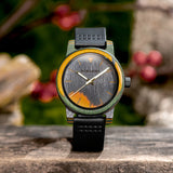 Wooden watch with black case and green strap on dark background
