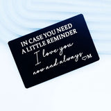 Matte black engraved metal wallet card angled on a pale blue and white surface