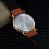Plain polished steel caseback of art dial watch shown with brown leather strap