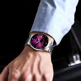 Silver watch with purple sunray dial worn on a wrist with a blue shirt cuff