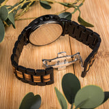 Two-tone wooden chronograph watch with cream dial on a wood surface with foliage