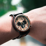 Wooden chronograph watch with cream dial worn on a wrist outdoors
