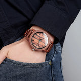 Wrist wearing a light wood watch with pale dial and denim sleeve