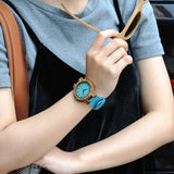Person wearing a bamboo watch with turquoise dial and teal strap