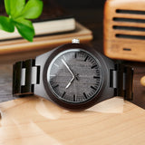 Wooden watch with pale silver dial and dark wood bracelet beside a knife block