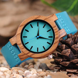 Bamboo watch with turquoise dial and teal strap on a pine cone and stone surface