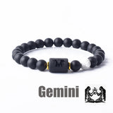 Dark stone bead bracelet with Gemini zodiac symbol charm