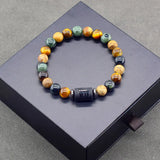 Natural stone bead bracelet with engraved zodiac bar charm on a dark display block