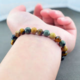 Natural stone bead zodiac bracelet worn on a wrist with a clenched hand