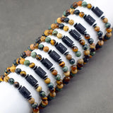 Several natural stone bead zodiac bracelets stacked on a grey surface