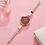 Rose gold women's watch with brown dial styled on pink background with roses