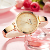 Rose gold slim watch with cream dial styled beside glassware and pink roses