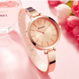 Rose gold slim women's watch styled beside pink flowers on a pale surface