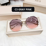 Gold frame curved sunglasses with gray to pink gradient lens in cream box