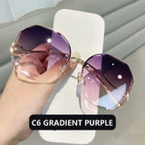 Hand holding curved sunglasses with gold frame and purple gradient lens