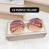 Gold frame curved sunglasses with purple to yellow gradient lens in cream box