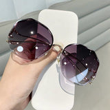 Hand holding curved sunglasses with gold frame and gray gradient lens