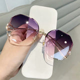 Hand holding curved sunglasses with gold frame and deep purple gradient lens