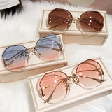 Three curved rimless sunglasses in cream gift boxes on white fur background