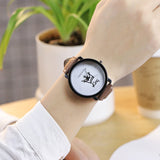 King and Queen leather strap watch worn on wrist near a potted plant