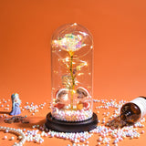 Gold foil rose in a glass dome with LED lights against an orange backdrop