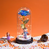 Pink and gold foil rose glowing under a glass dome with fairy lights