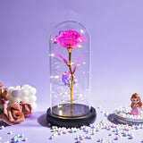 Bright pink foil rose in a glass dome with fairy lights on a dark base