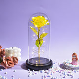 Golden yellow foil rose under a glass dome with fairy lights on a wooden base