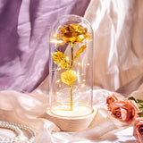 Gold foil rose under a glass dome on a black base with battery switch visible