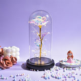 Yellow rose with green leaves in a clear glass dome on a wooden base