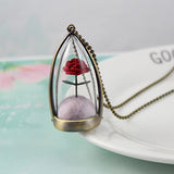 Rose terrarium glass dome pendant displayed upright on a small stand