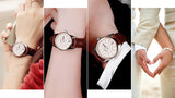 Two wrists clasped together each wearing a brown leather strap watch